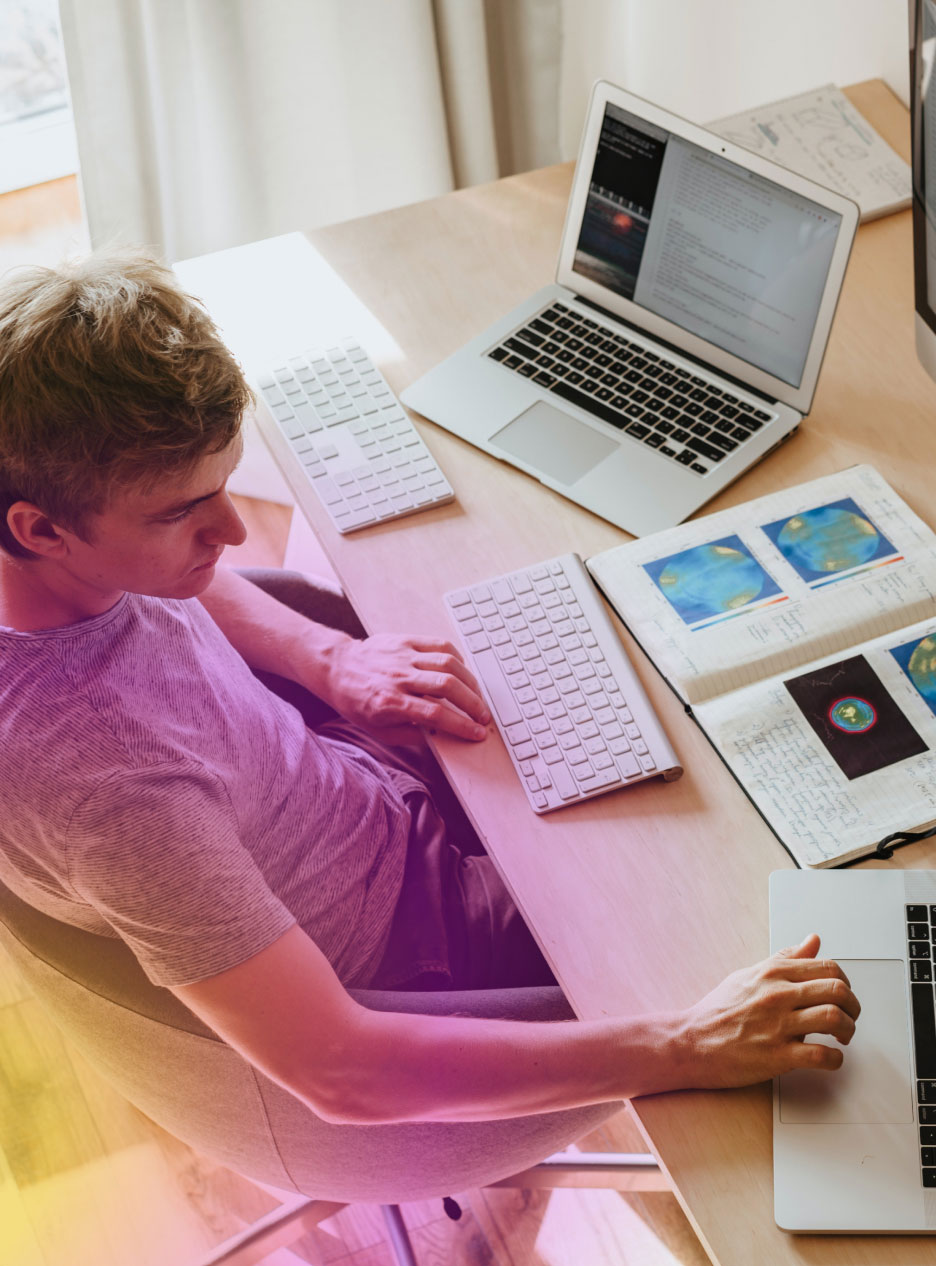 info-2 "Young Man is seen Working Modern desk setup, surrounded by multiple Keyboards, Laptop, colorful scientific diagrams."