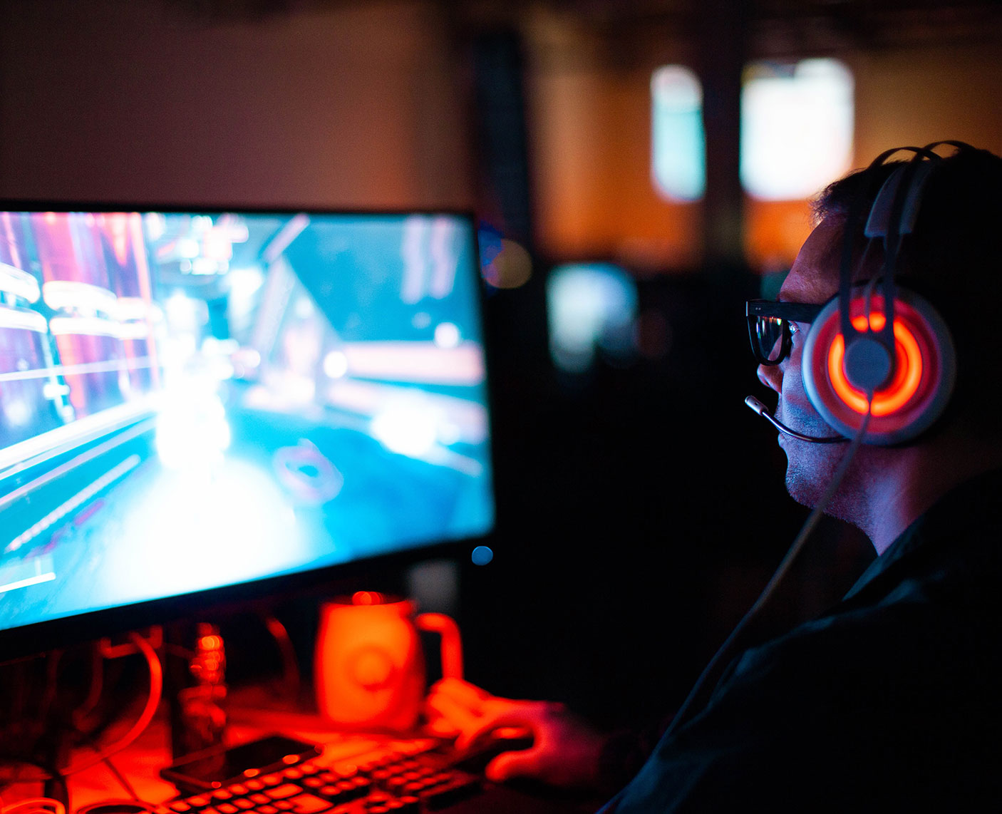 "Gamer wearing headphones playing on high-resolution screen in dark room, symbolizing digital engagement ."
